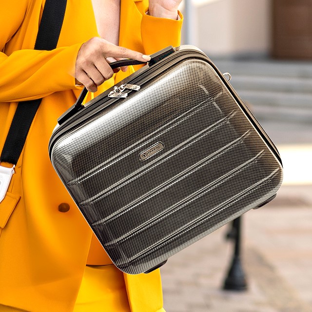 Frau mit Sonnengelben Blazer transportiert CHECK.IN Beautycase in grau